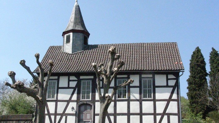 Das Bild zeigt ein traditionelles deutsches Fachwerkhaus mit einem kleinen Turm und einem Wetterhahn.