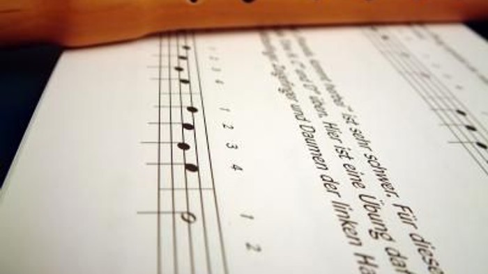 Ein Musikblatt mit Noten und eine Holzflöte.