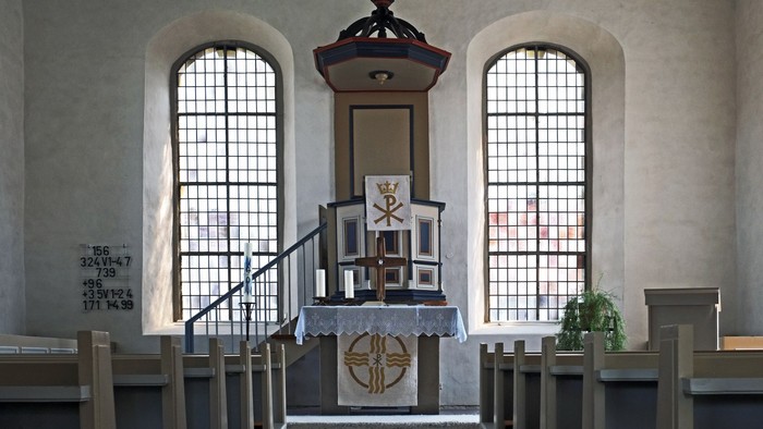 Kircheninneres mit Altar, Buntglasfenstern und Topfpflanze