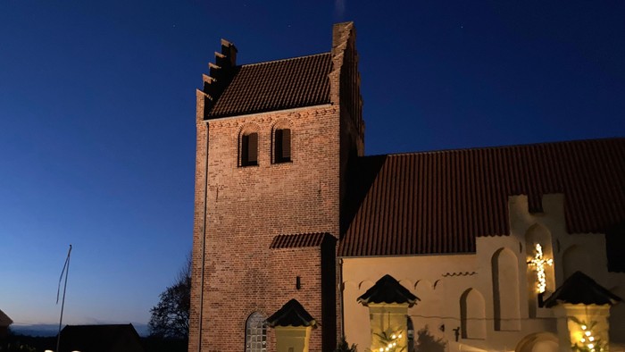 En belysning og juletrær foran kirke
