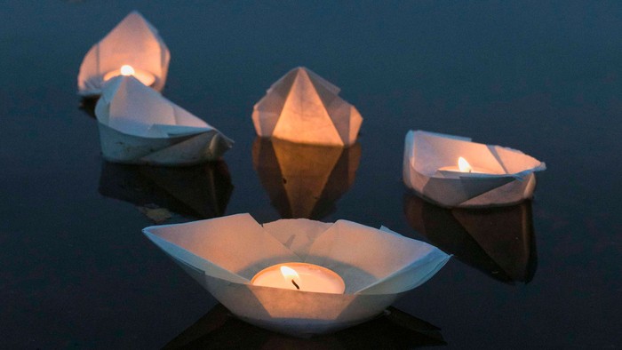 Papierlaternen treiben nachts auf dem Wasser.