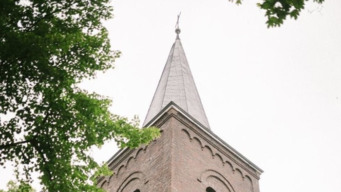 Der Kirchturm aus Ziegeln ragt hoch in den Himmel
