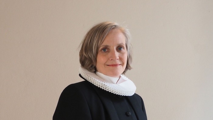 Kvinde i sort kaptajnmø, hvid krage og hvid kuffe.