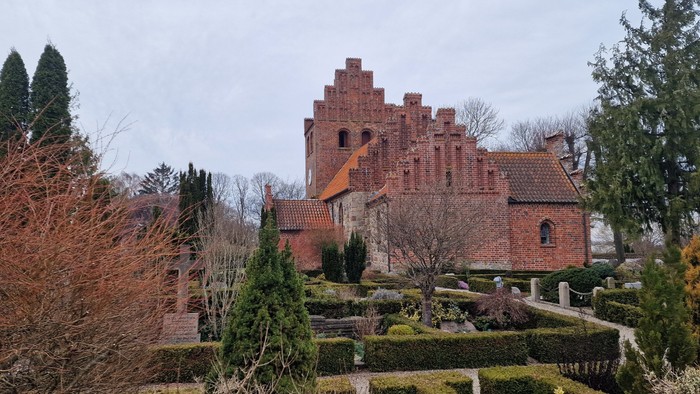 Et stort, gammelt teglsteinslot med en have og træer