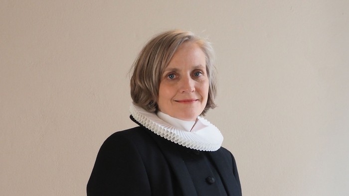 Kvinde i sort kaptajnmø, hvid krage og hvid kuffe.