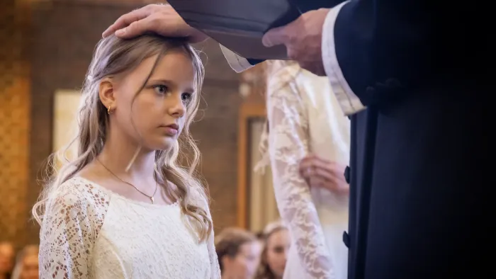 En ung pige modtager et slør fra en ældre kvinde under en formel ceremoni.