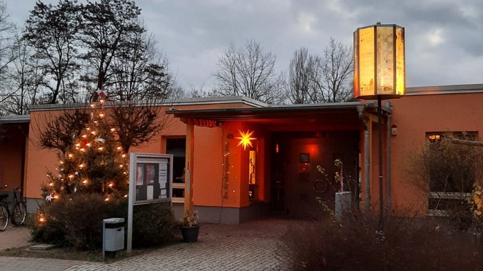 Ein orangefarbenes Gebäude mit Weihnachtsbeleuchtung und einem beleuchteten Eingang.