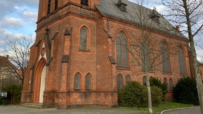 Große rote Ziegelkirche mit hohem Turm und spitzen Fenstern.