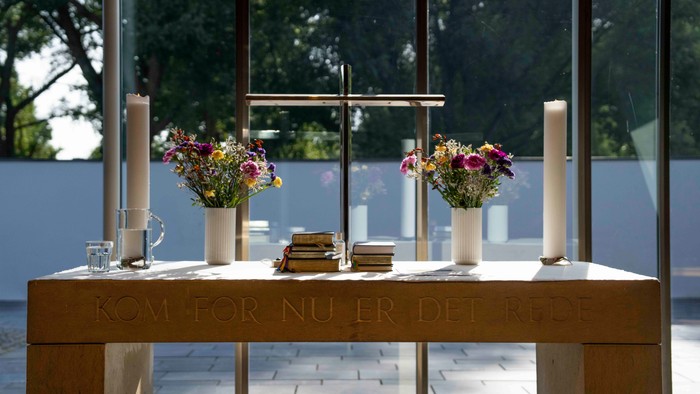 Bord med blomster, lysstake og bøger i lyset