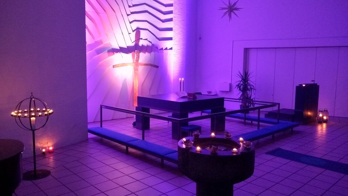 En rolig kirkerum med lys og blomster.