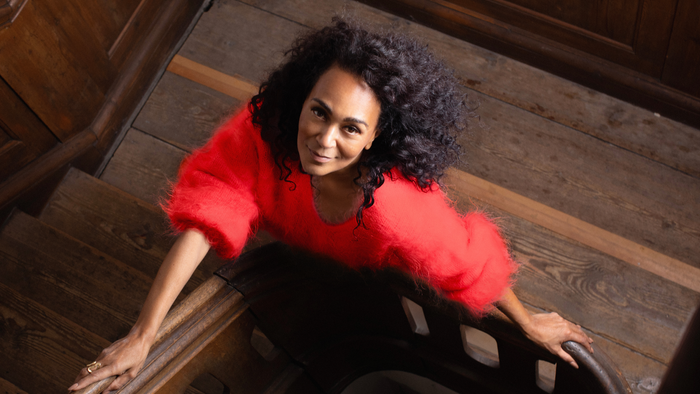 En kvinde i rød og sort outfit sidder på trætrappen.