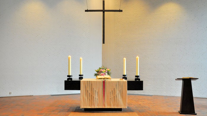 Einfache Kirche mit Holzaltar, Kerzen und Kreuz an der Wand