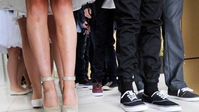 En gruppe af mennesker står sammen, deres ben og sko er synlige.