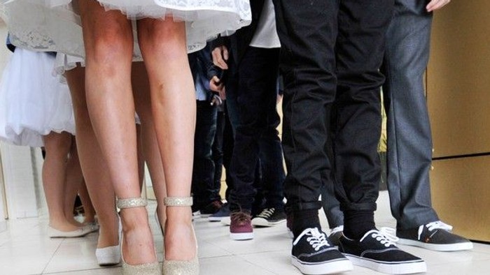 En gruppe af mennesker står sammen, deres ben og sko er synlige.