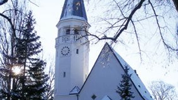 Weiße Kirche im Winter mit hohem Turm und Uhr.