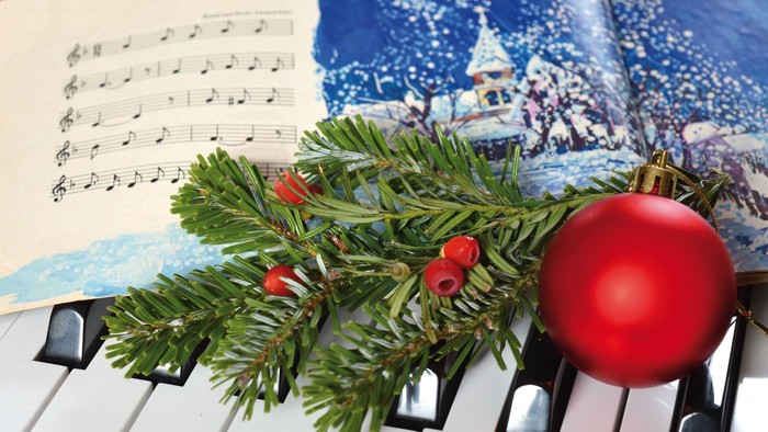 Klaviertasten mit Tannenzweig, Christbaumglocke und Notenblatt