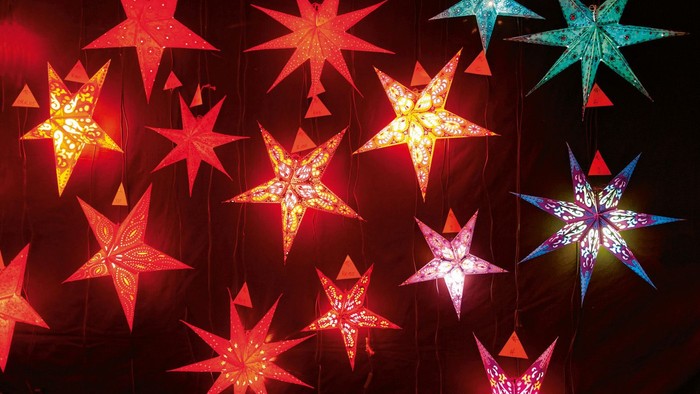 Leuchtende Sterne in verschiedenen Farben hängen im Dunkeln