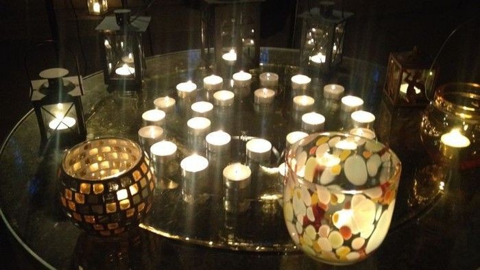 Kerzen in verschiedenen Haltern auf einem Glastisch