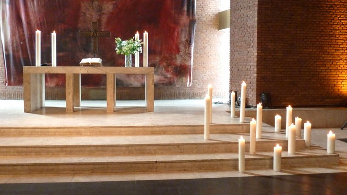 Holztreppe mit zahlreichen Kerzen, davor ein Tisch mit weiteren Kerzen und einer Vase