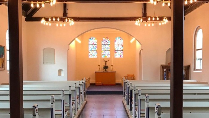 Indenrigsudsigt på kirke med bænkepladser og alter.