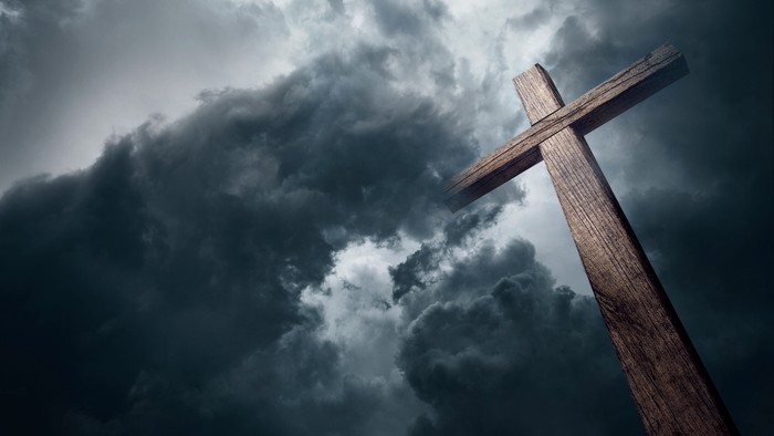 Ein hölzernes Kreuz vor dunklen Wolken