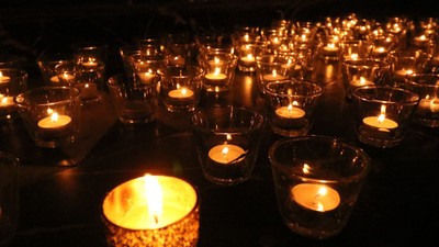 Viele brennende Kerzen in Glasgefäßen auf dunklem Hintergrund