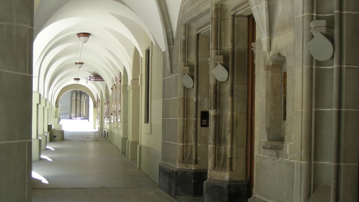 Ein langer, gewölbter Flur mit steinernen Säulen und Türen.