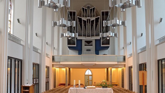 Große, helle Kirche mit hängenden Lampen und Altar