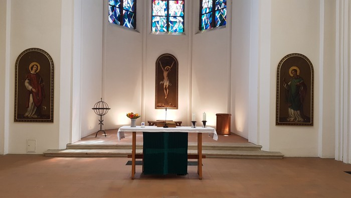 Ein Kircheninneres mit Altar, Stufen und Bildern an den Wänden