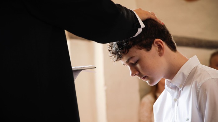 En person håndterer en ung drengs halsbånd i en formel indkledning.