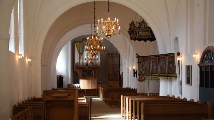 Indenrigsrom i kirke med orgel og bænke.