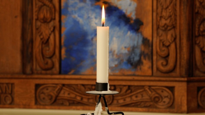 Elegant lysestage på et rundt bord med dekorativt sand og et centralt tændt lys.