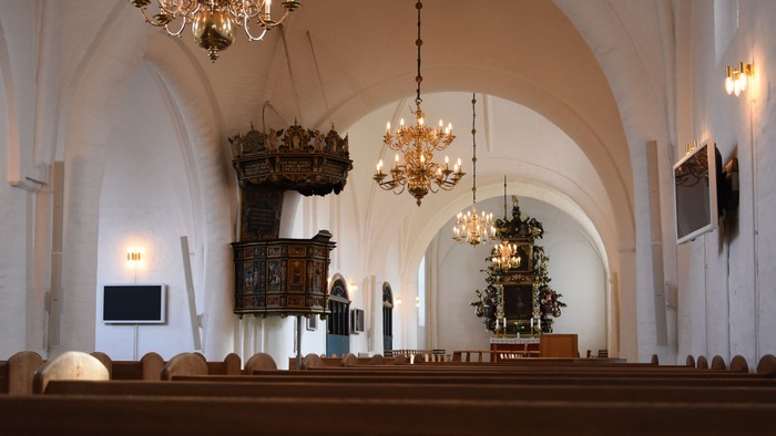 Indenrigs af kirke med høje hvelvede og belysninger