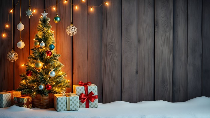 Weihnachtsbaum mit Geschenken und Dekoration vor einer Holzwand.