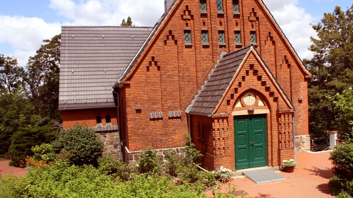 Kapelle aus roten Ziegeln. Blick auf grüne Eingangstür.