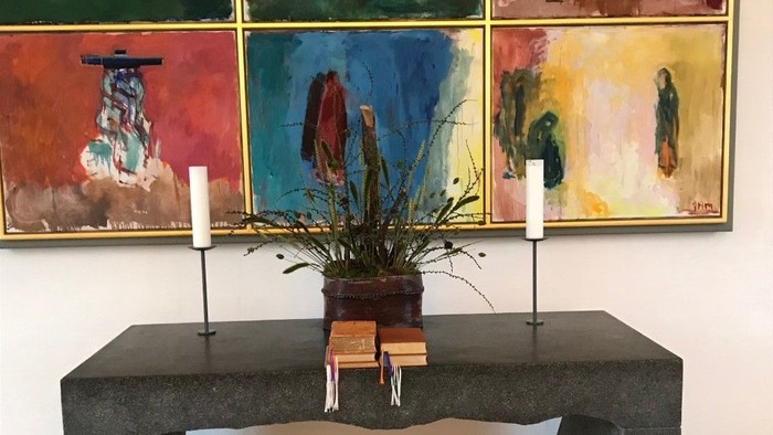 En moderne indretning med sort bord, to lysekøn, og farvede malerier på væggen