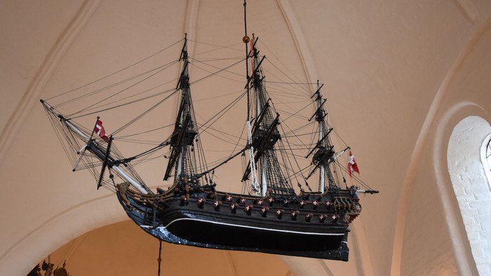 Et skibsmodel hænger fra taket i en kirke.