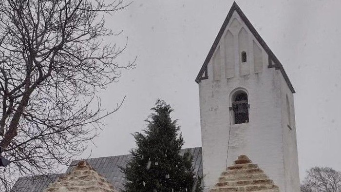 En snowy kirke med to tårne og en træ.