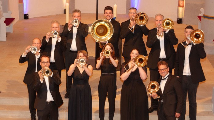 Eine formelle Blechbläsergruppe, die in eleganter Kleidung mit Blechblasinstrumenten posiert.