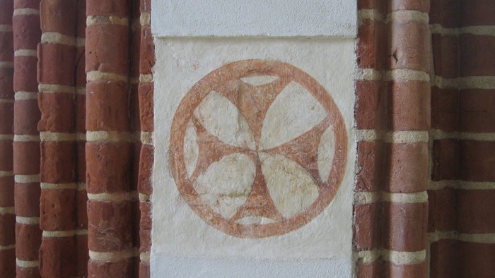 En hvidsten med et rødt symbol på en mur af røde teglsten