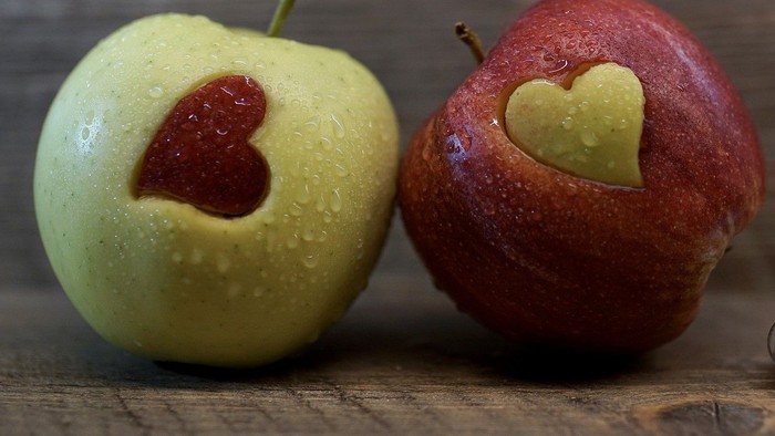 Zwei Äpfel mit Herzen darauf auf Holzoberfläche