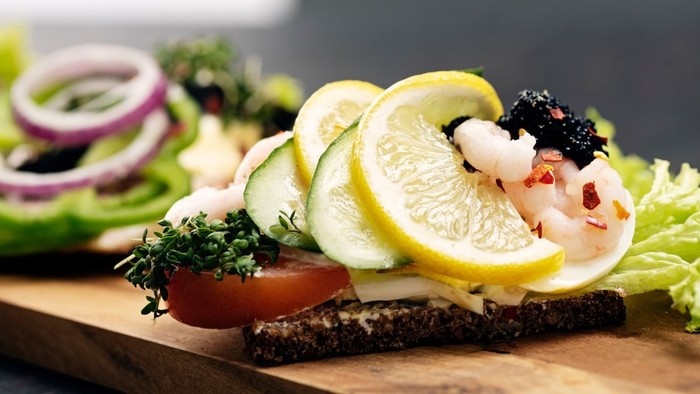 En smørrebrød med krabbe, citron og grønne salatblade