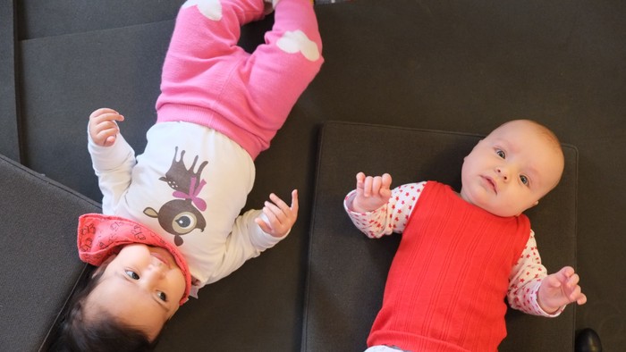 To børn ligger på magen på gulvmatte