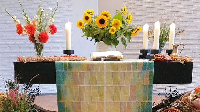 Ein farbenfroher Altar mit Sonnenblumen und Kerzen in einer Kirche