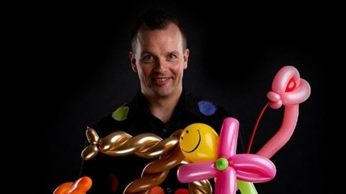 En person holder kreativt en samling af farverige ballonfigurer og kreationer.