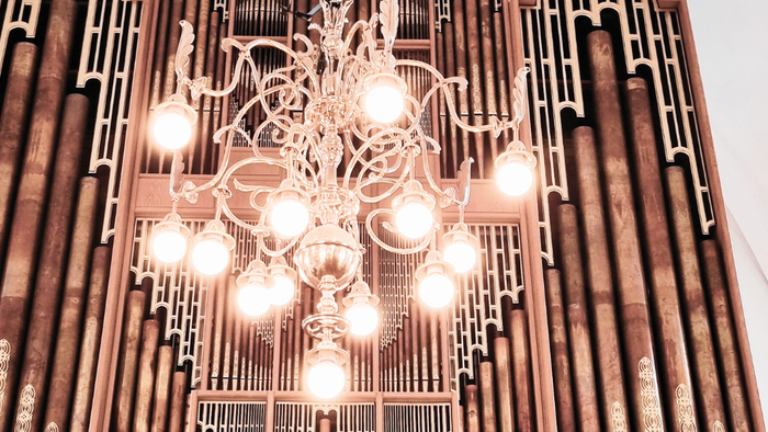 En stor og luksuriøs kælderkandelier hænger fra loftet i et rum med høje vinduer.