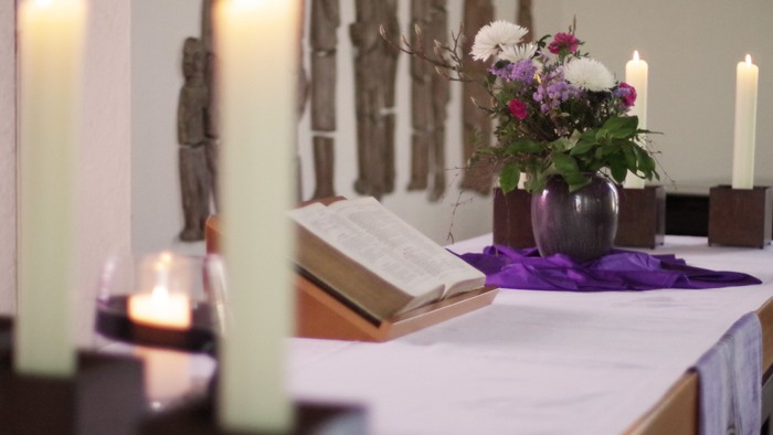 Tisch mit Kerzen, Buch und Blumen in einer Vase