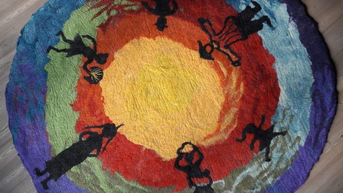 Bunter Teppich mit schwarzen Silhouetten von Menschen im Kreis