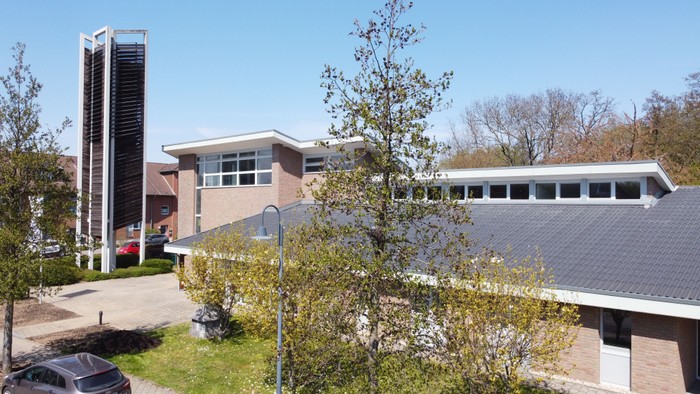 Modernes Gebäude mit hoher Säule und parkähnlichem Garten