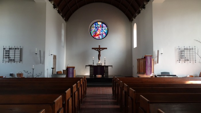 Kirchlicher Innenraum mit Kreuz und Buntglasfenster